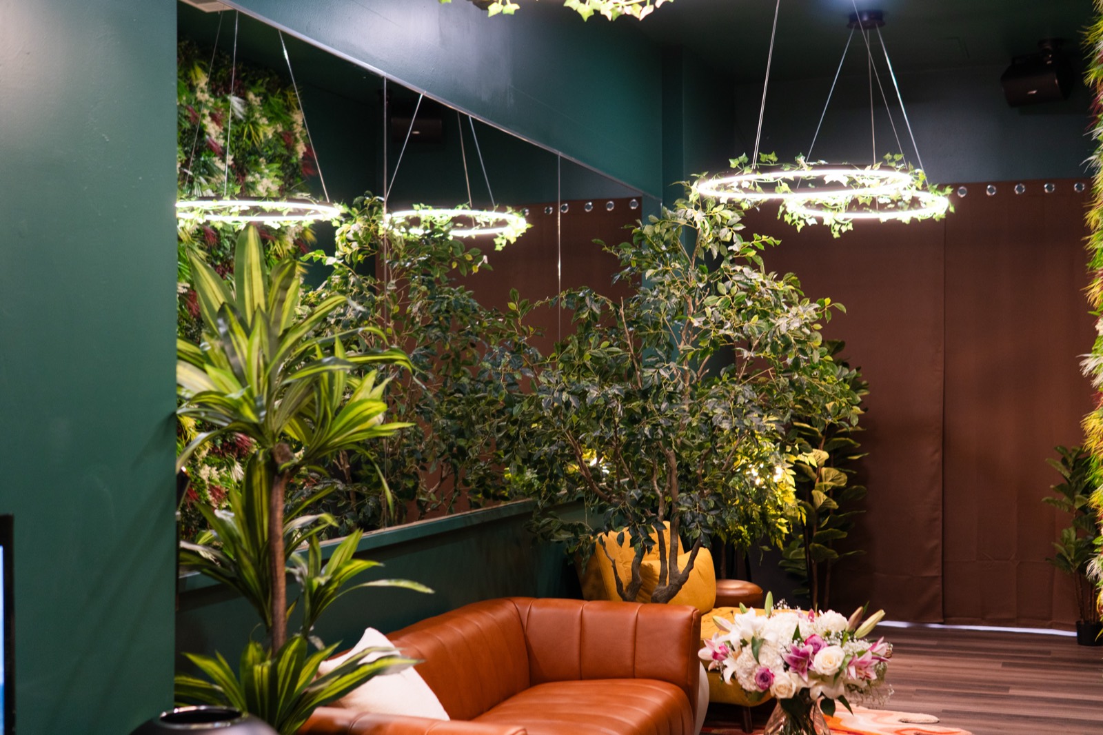 The lounge: leather sofa, living plant wall, and ring chandeliers